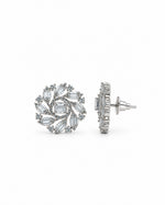 A pair of silver-toned stud earrings with a floral, leaf-like arrangement of clear baguette and round stones, shown from the front and side on a white background.